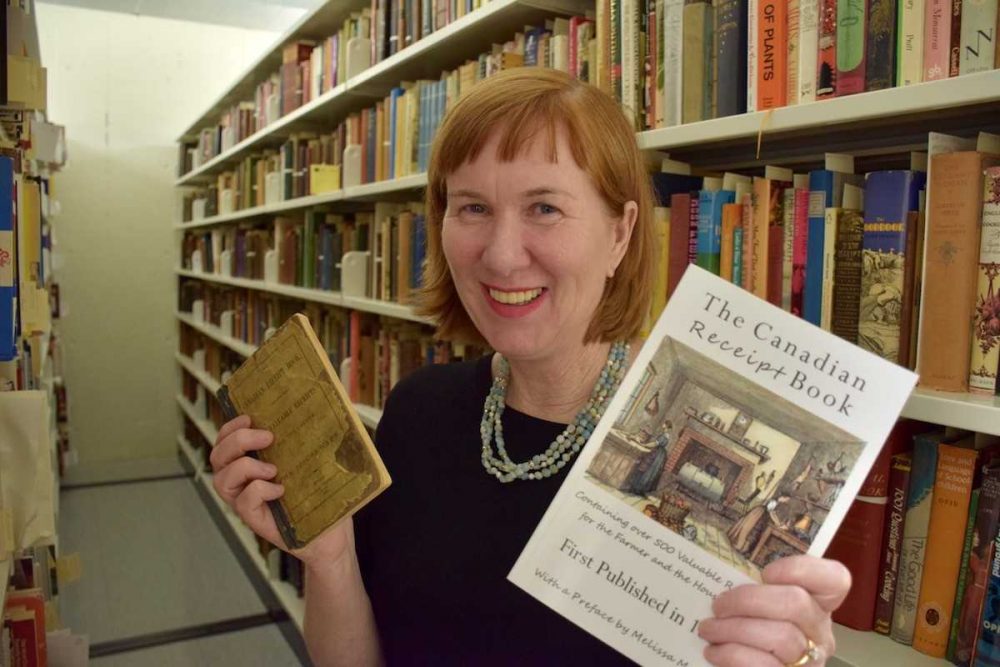 Melissa McAfee holding the original The Canadian Receipt Book and the republished copy