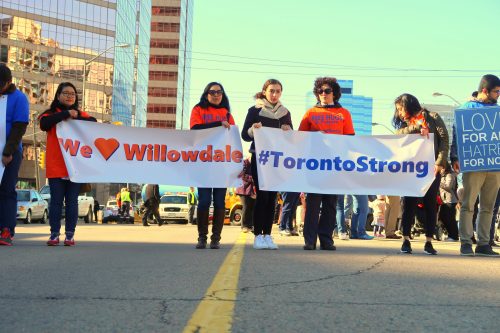 People line up with "we love Willowdale" sign and a #TorontoStrong sign for a march and vigil