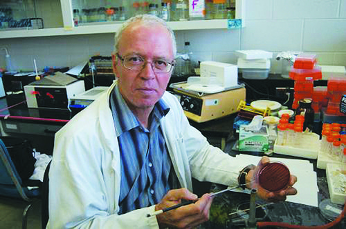 Prof. John Prescott in a lab coat showing a petrie dish sample