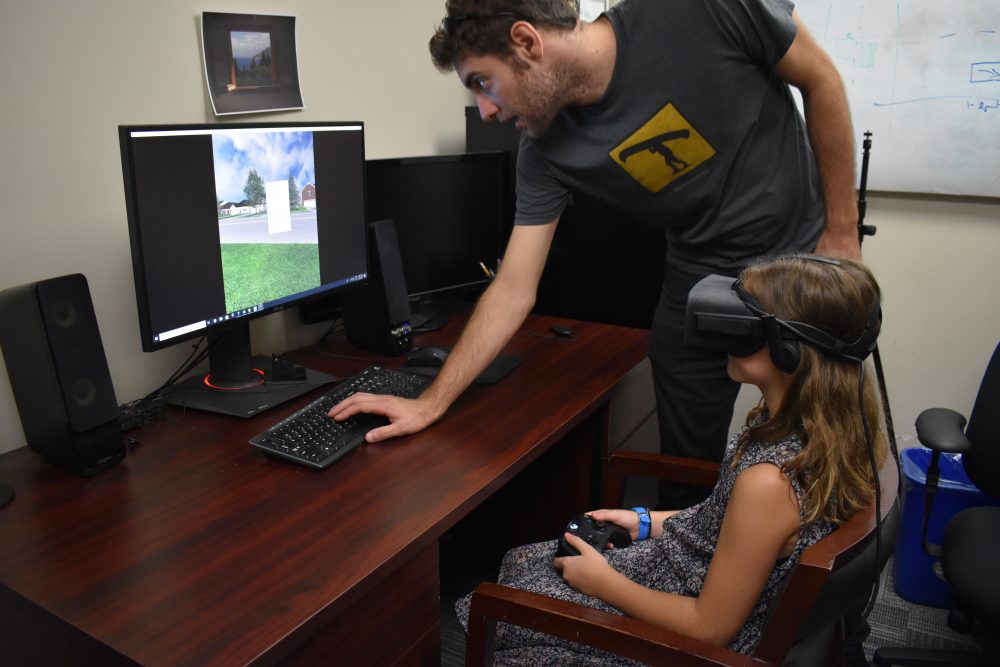 A young girl uses VR goggles and gaming console to play game that teachers her how to cross the street saftely