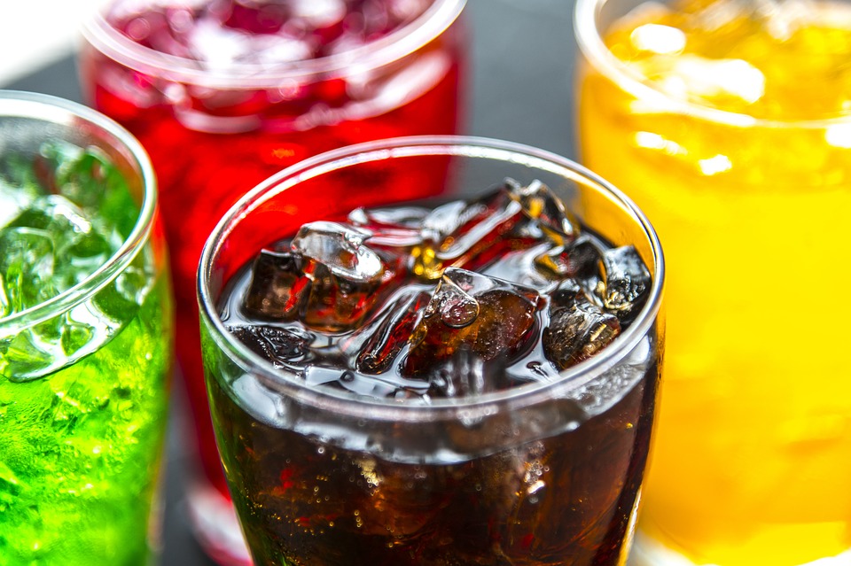 glasses of different types of sodas with ice cubes