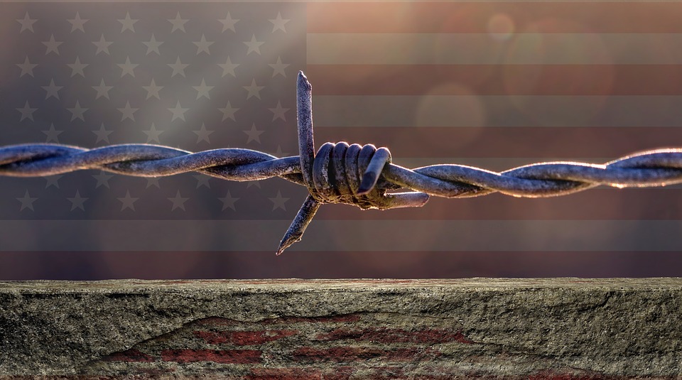 american flag with barbed wire fence across