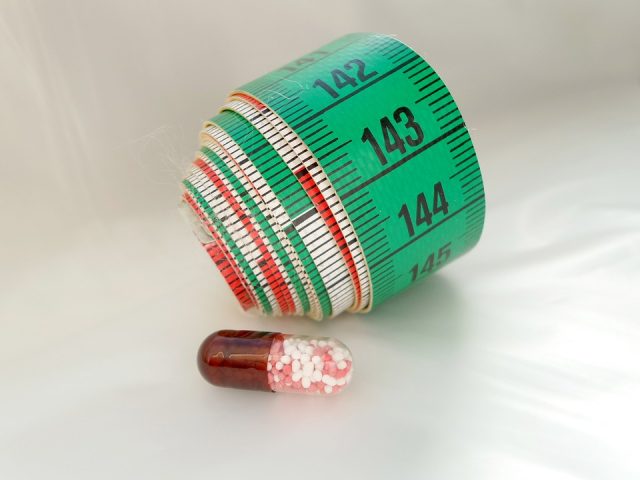 measuring tape rolled up and a pill
