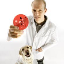 image of Prof. Scott Weese holding up a petri dish with a dog next to him