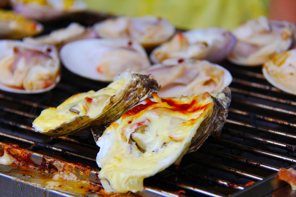 Cooked oysters on grill with cheese on top
