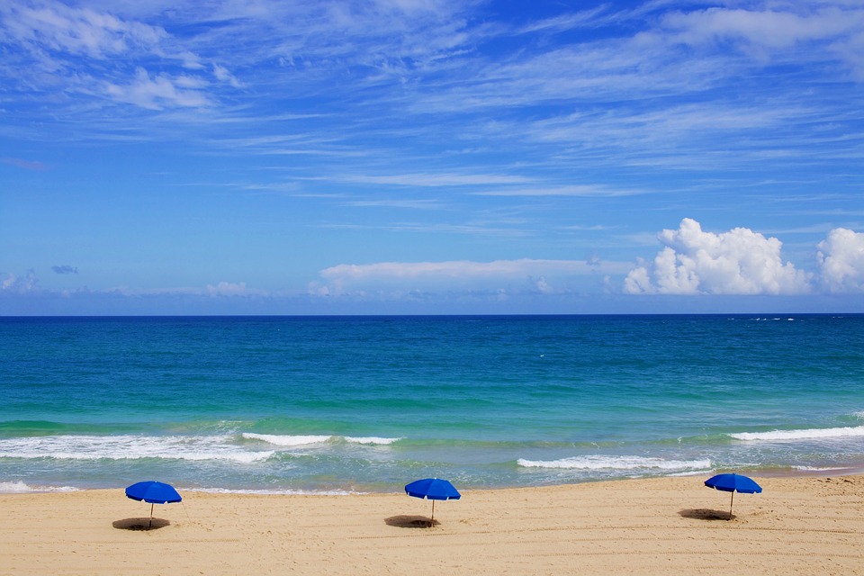 Beach, ocean, three blue umbrellas on sand
