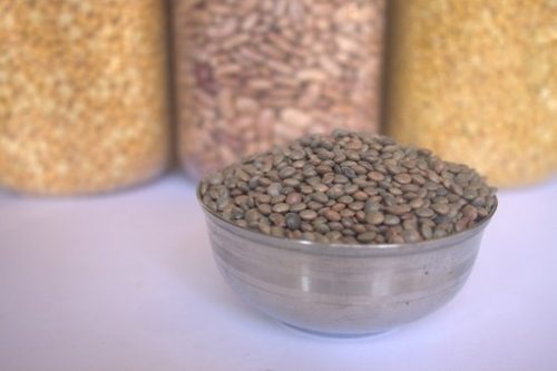 photo of a bowl full of lentils with canisters of different pulses in the background