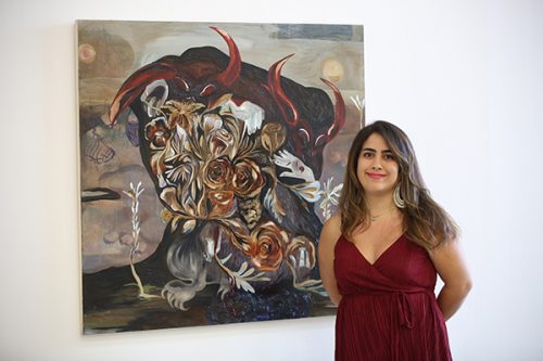 photo of Amanda Boulos standing next to her winning painting 