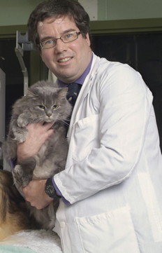 photo of Prof. Paul Woods in a white lab coat holding a grey cat
