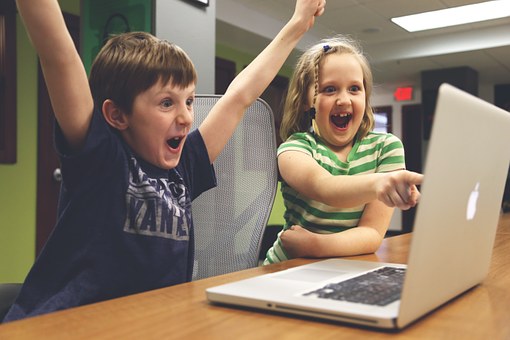 two kids pointing at a computer screen