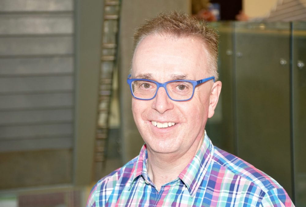 Professor smiling in checkered shirt