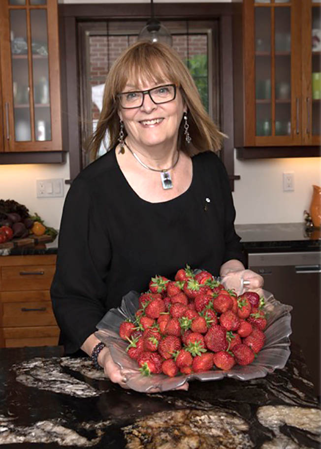 Anita Stewart holds a platter of strawberries in a kitchen