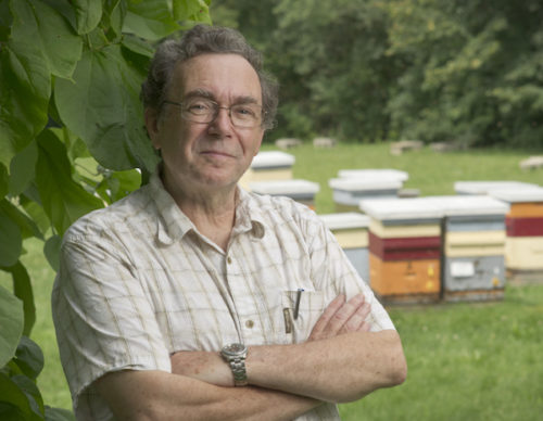 Professor with folded arms and beehives in the background
