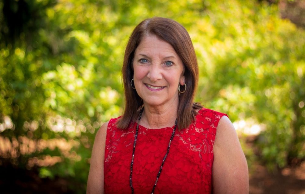 Dr. Barbara Morrongiello in red stands against background of greenery.