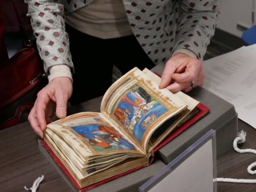 A woman turns the pages of one of the manuscripts.
