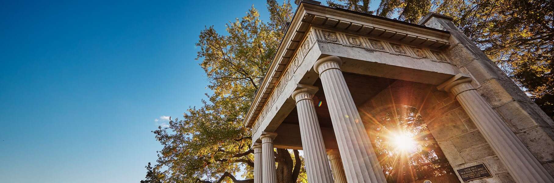 The sun shines through the U of G Portico as it sets.