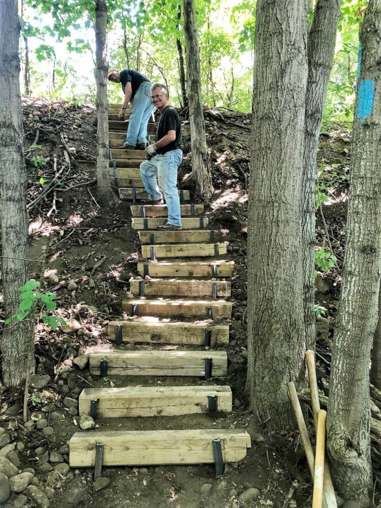 Two men help install one of 22 new steps along the trail