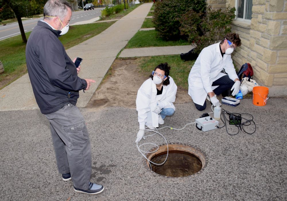 Engineering professor Ed McBean takes samples of wastewater at the University's East Residence with student research assistants Jonathan Evans and Melissa Novacefski. 