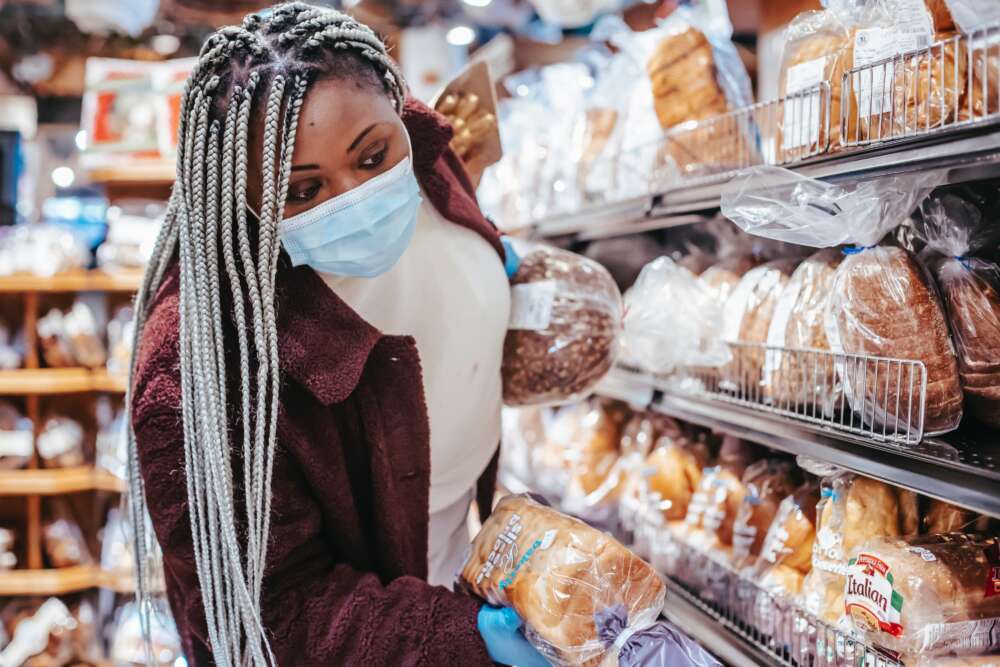 A woman wearing a mask shops for packaged bread