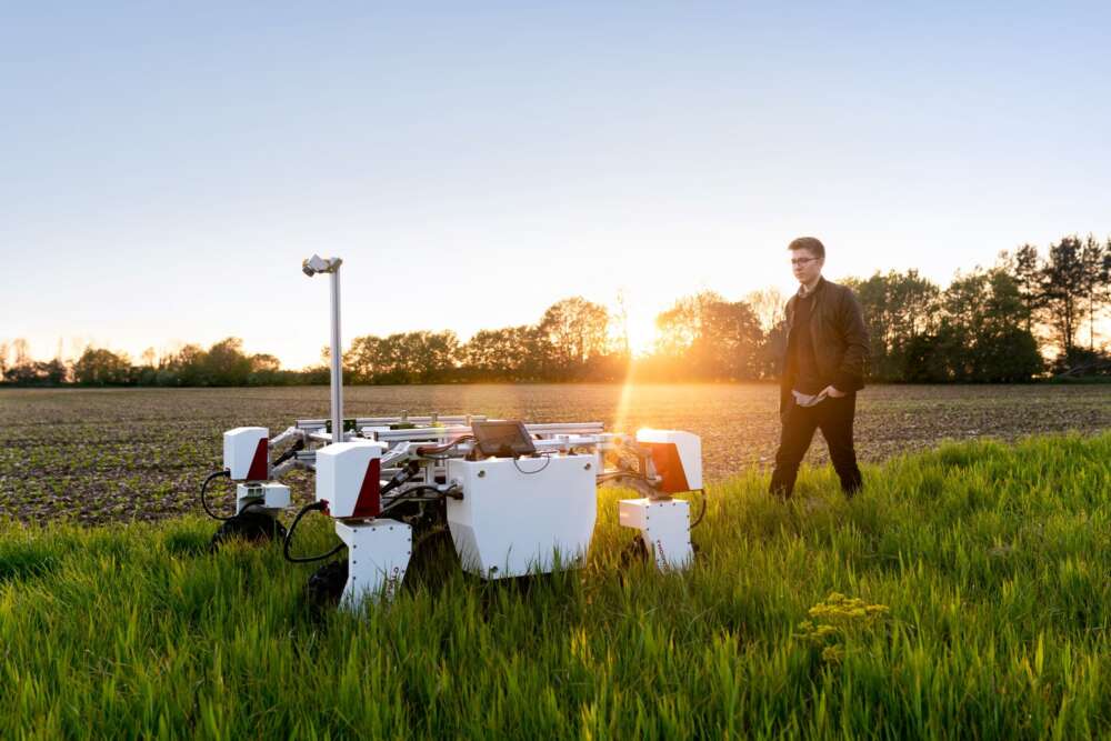 Male mechanical engineer with agricultural robot in field