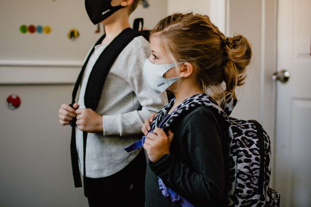 two schoolchildren wear masks and backpacks