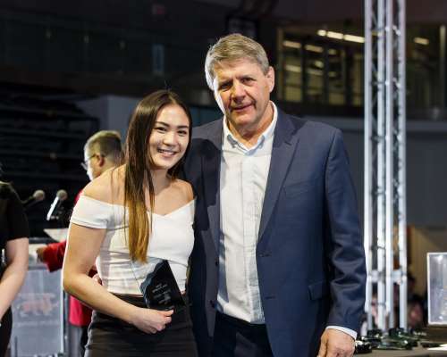 Young Asian woman holding award with man in blue jacket