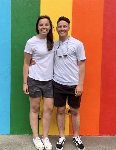Young man and woman, Pride rainbow wall behind them