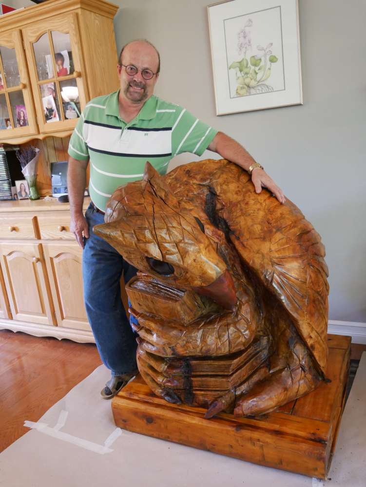 Professor standing with large carving of the mythic creature gryphon