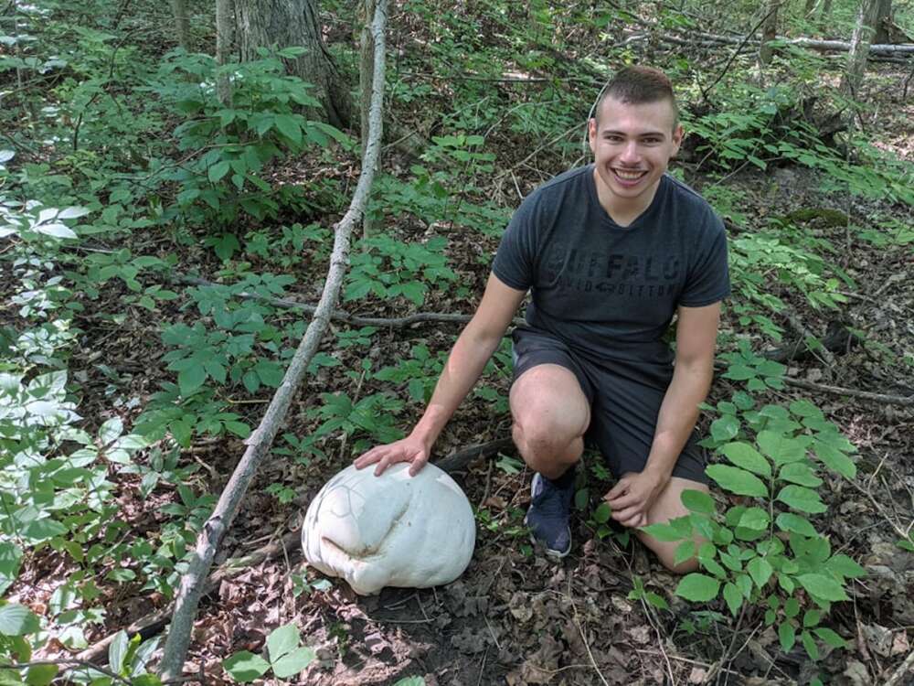 Young man in forest with giant puff ball