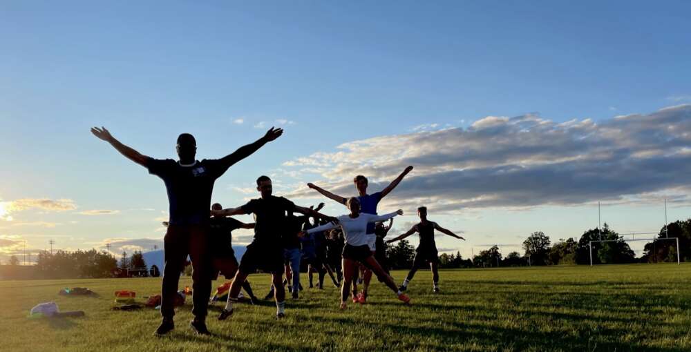 About 10 people stretching on an athletic field
