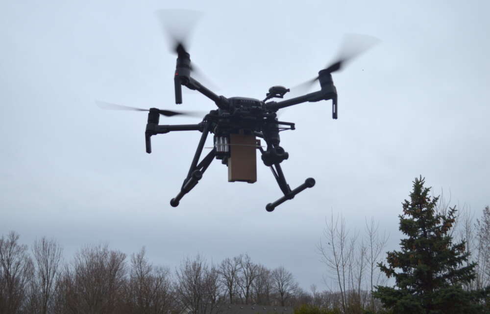 A large drone is shown flying over trees