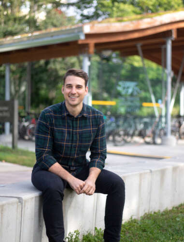 Sustainability manager Brandon Raco sits on a concrete bench on the U of G campus