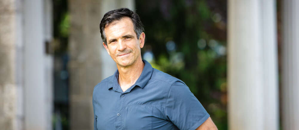 A man in blue shirt stands before the U of G portico