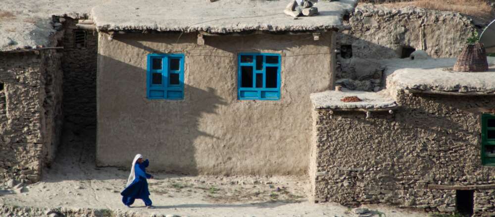woman in blue dress sitting on gray concrete wall during daytime