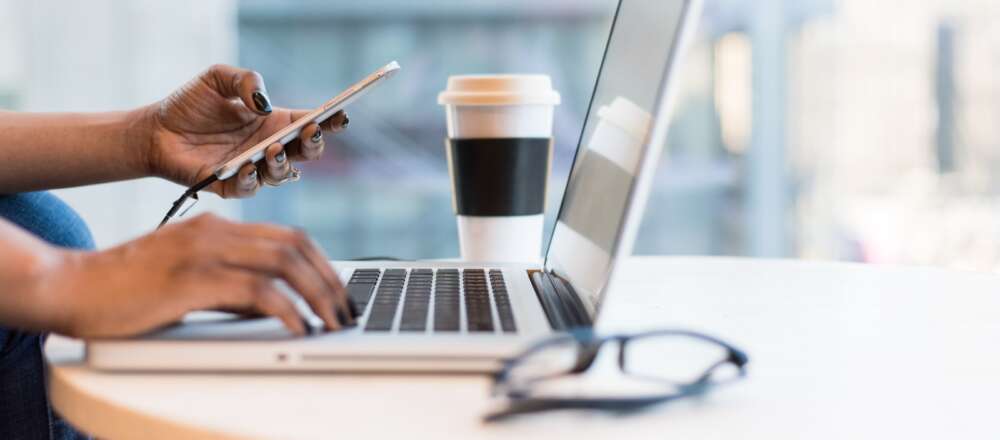 A person using smartphone and MacBook