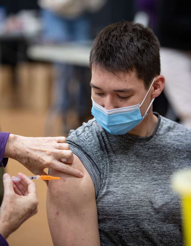 A person looks at their shoulder while they receive a vaccination
