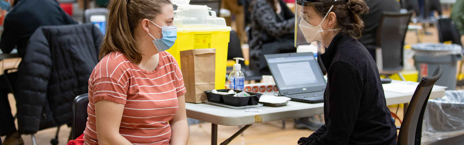 Two people sit at a table in the U of G vaccination centre on campus