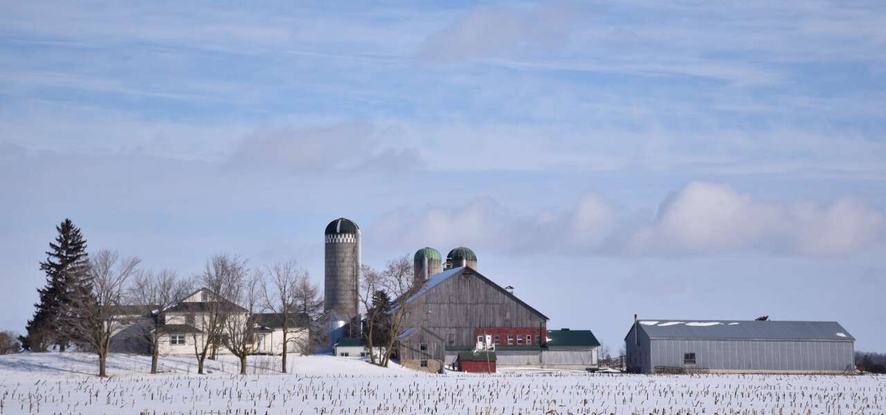 A wide shot of a farm and field in winter