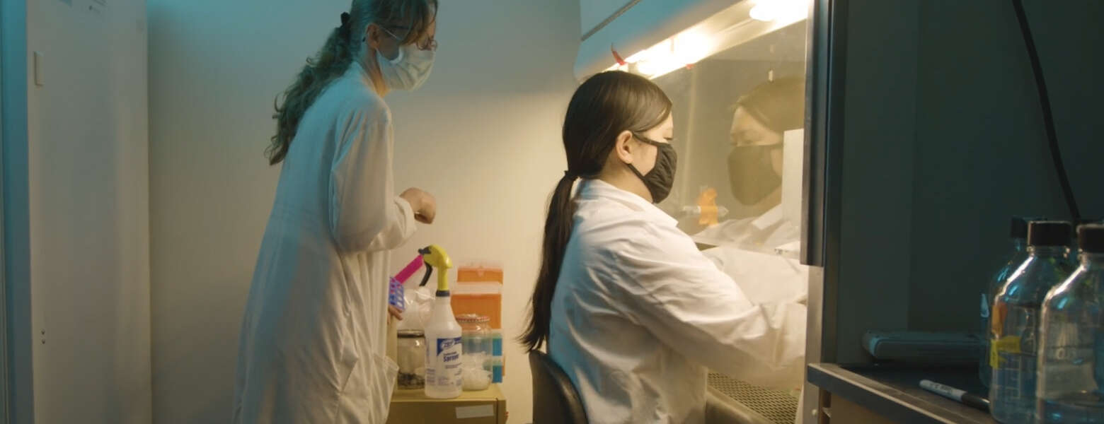 Dr. Sarah Wootton in white labcoat with one other person in the lab.