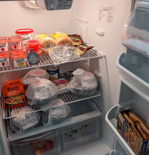 The interior of a fridge with yogourts, rice packages, bagels and more