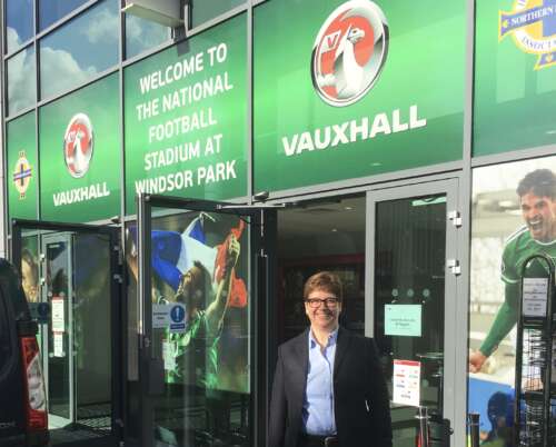 Dr. Ann Pegoraro stands in front of the doors to the National Football Stadium at Windsor Park.