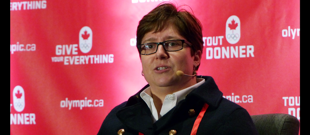 Dr. Ann Pegoraro speaks on panel in front of red and white background