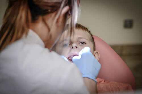 a dentist peers into the mouth of a child in a dental office