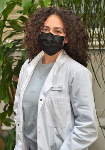 A woman wearing a lab coat smiles for the camera