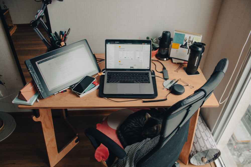 A work from home set up with a laptop and tablet, and office accessories, on a desk.