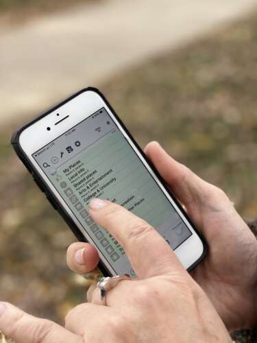 A person scrolls through the locations listed in the app for BlindSquare
