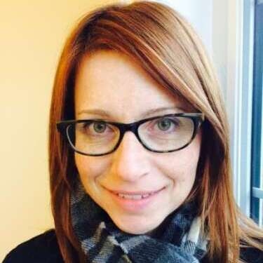 Dr. Candace Johnson takes a selfie in front of a window and pale yellow wall.