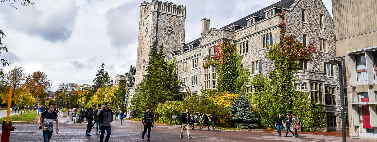 A wide view of students walking past ivy-covered Johnston Hall