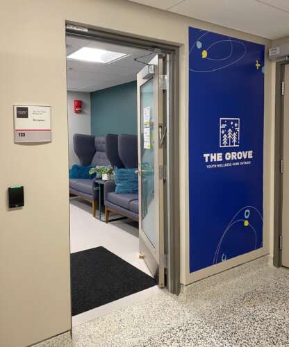 A waiting room is showm with a large The Grove Hub sign out front