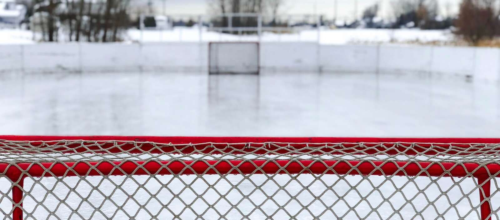 A red and white goal net on ice field